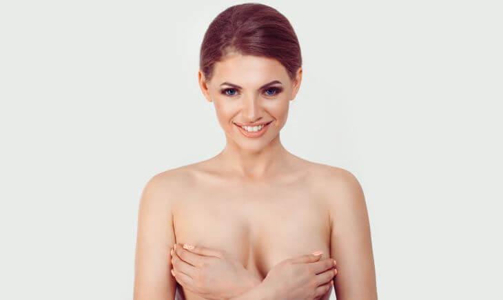 Happy beautiful woman covering her breasts with her hands