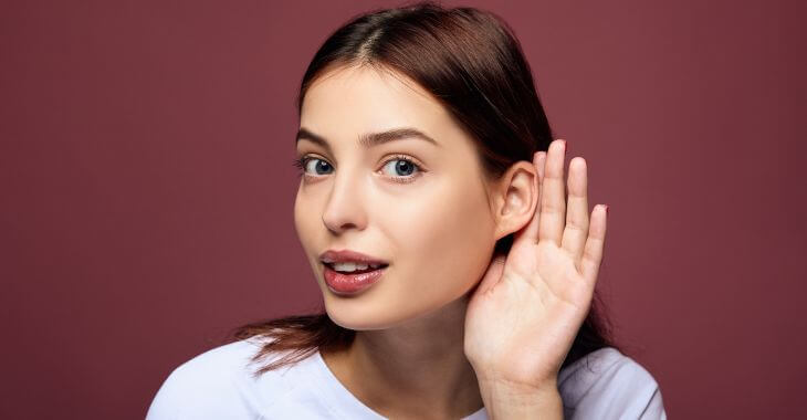 a girl with a hand by her ear trying to hear carefully