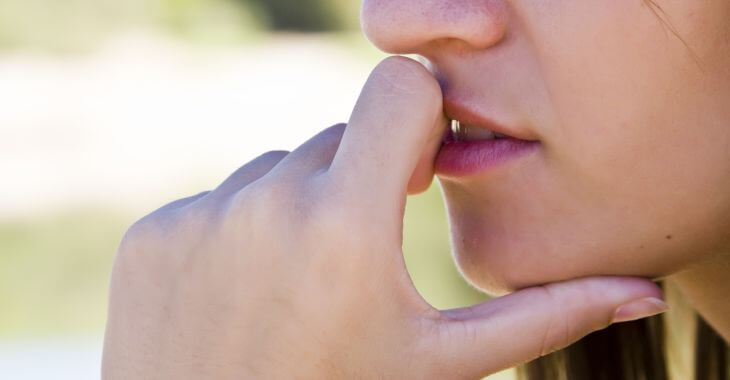 A concerned young woman covering her lip with a scar on it