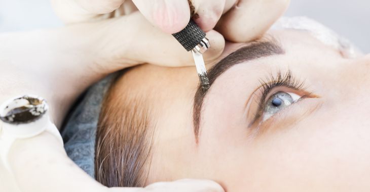 A woman undergoing eyebrows microblading procedure