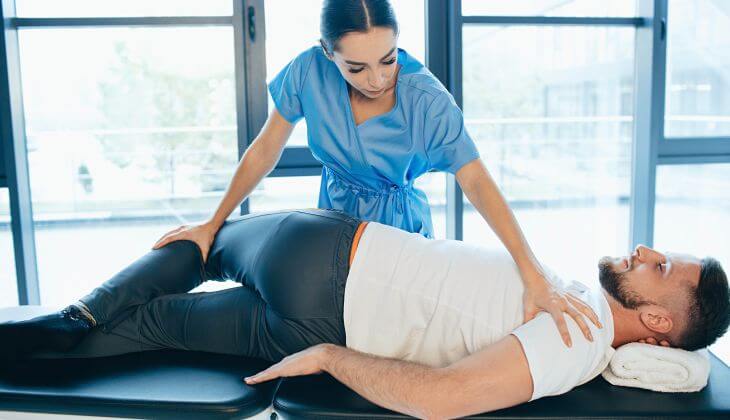 A man and a physical therapist providing a therapy for lumbar pain and sciatica nerve inflammation  